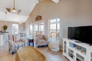 sala de estar con TV de pantalla plana y sillas en Little House on the Bay, en Galveston