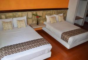 two beds sitting next to each other in a room at Hotel Casa Arena in Zihuatanejo