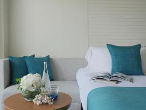 a bed with a book and a vase of flowers on a table at ANA InterContinental Manza Beach Resort by IHG in Onna