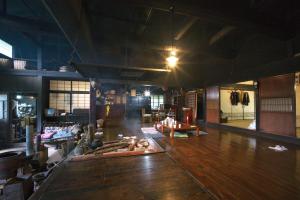 a large room with a wooden floor and a room with tables at Kamiya Rare Experience in a 180 Year Old Farmhouse Milky Way Irori Fire and Nature! in Iida