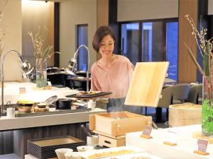 a woman standing behind a counter in a kitchen at Lotte Arai Resort in Myoko
