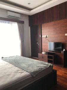 a bedroom with a bed and a flat screen tv at Villa Ulin A3 at Villa Ubud Anyer in Serang