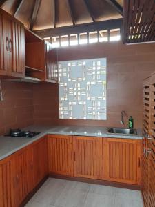 een keuken met houten kasten, een wastafel en een raam bij Villa Ulin A3 at Villa Ubud Anyer in Serang