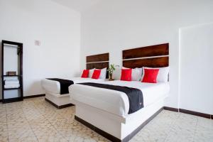 duas camas num quarto de hotel com almofadas vermelhas em Hotel Pósada Maria Isabel em Atlixco