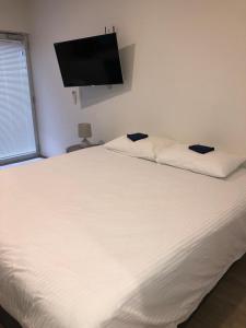 sypialnia z białym łóżkiem i telewizorem z płaskim ekranem w obiekcie Bondi Beach Studios Suite w mieście Sydney