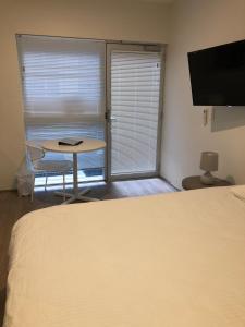 a bedroom with a bed and a table and a window at Bondi Beach Studios Suite in Sydney