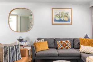 a living room with a gray couch and a mirror at City Courtyard Two Apartment in Mount Gambier