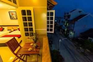 a room with a balcony with a bed and a table at Moon's Homestay in Hoi An