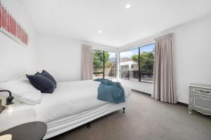 a bedroom with a white bed and a large window at Kiwi style home! Views of lake. Large outdoor area in Queenstown