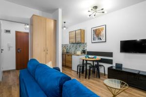 a living room with a blue couch and a kitchen at Sleepway Apartments - Modern Dream in Poznań