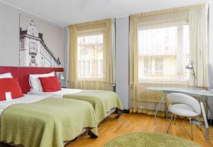 a room with two beds and a desk and two windows at Original Sokos Hotel Albert in Helsinki