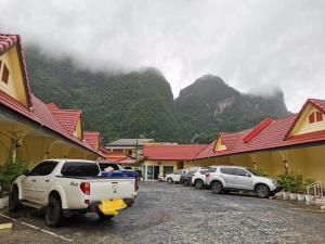 a group of cars parked in a parking lot with mountains in the background at Rachawadee House in Phangnga