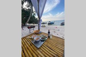 Ko Sukon的住宿－Jayden's HomeStay，海滩上的餐桌,带食物和一瓶葡萄酒