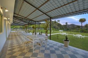 a patio with tables and chairs and a view of a park at The Mount Bungalow Mount Abu in Mount Ābu