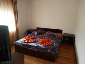 a bedroom with a bed with two orange towels on it at Varipatti House in Slatina