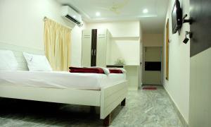 a bedroom with a white bed in a room at Raya's Executive Homes in Kumbakonam