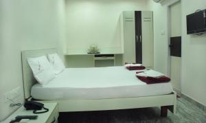 a small white bedroom with a bed and a desk at Raya's Executive Homes in Kumbakonam