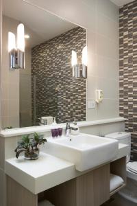Un baño con lavabo, espejo e inodoro. en Citadines Uplands Kuching, en Kuching