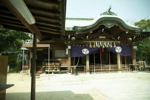 un santuario con una bandera azul delante de él en HOTEL KARAE en Karatsu