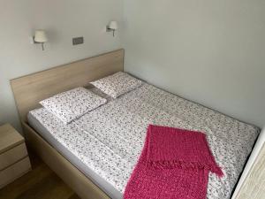 Un dormitorio con una cama con una manta rosa. en Apartament w Pucku, en Puck