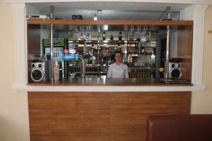 a man standing behind a bar with a counter with speakers at Green Hotel in Almaty