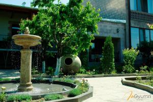 a fountain in front of a building with a tree at In Gyumri in Gyumri