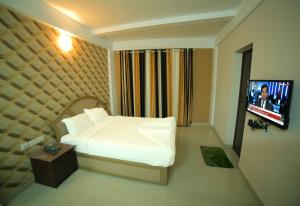 a bedroom with a bed and a flat screen tv at Hotel Falcon in Trivandrum