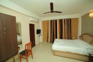 a bedroom with a bed and a chair and a window at Hotel Falcon in Trivandrum