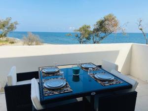 une table bleue avec des chaises et des assiettes sur une table donnant sur l'océan dans l'établissement Résidence Marina Di Bravone, à Linguizzetta