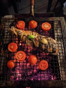 a grill with some meat and tomatoes on it at Urban Nomads Pune Riverside CoLive CoWork in Pune