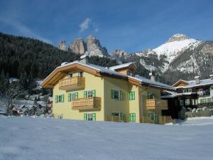 a building in the snow with mountains in the background at Residence Ercabuan in Campitello di Fassa