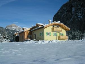 a house in the snow in front of a mountain at Residence Ercabuan in Campitello di Fassa