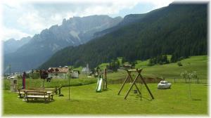 a playground in a field with mountains in the background at Residence Ercabuan in Campitello di Fassa