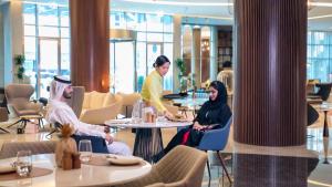 a group of people sitting around a table in a restaurant at Pullman Sharjah in Sharjah