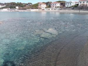 a body of water with a beach and buildings at Caletta Beach in Castiglioncello