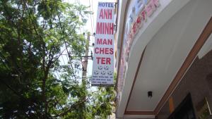 a sign hanging from the side of a building with trees at Anh Minh - Manchester Hotel Tran Phu Beach Nha Trang in Nha Trang