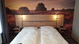 1 dormitorio con 1 cama con una pintura en la pared en Hotel-Restaurant Zur Linde, en Secklendorf