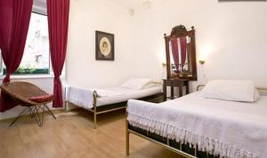 a bedroom with two beds and a chair and a window at Old Town Budget in Dubrovnik