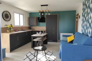 ein Wohnzimmer mit einem blauen Sofa und einer Küche in der Unterkunft Au bonheur des Landes Logement neuf tout confort proche forêt et ville in Colombiers