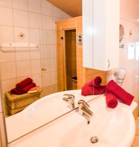 a bathroom with a sink and a tub with red towels at Ferienwohnungen Schwalbennest in Mauterndorf