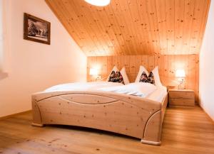 a large bed in a room with a wooden ceiling at Ferienwohnungen Schwalbennest in Mauterndorf
