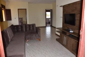 a living room with a brown couch and a flat screen tv at Residencia La maison Uruau in Uruau