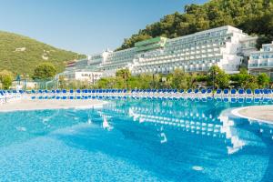 einem großen Pool mit blauen Stühlen und einem Gebäude in der Unterkunft Hotel Hedera - Maslinica Hotels & Resorts in Rabac