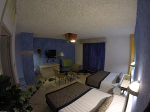 a hotel room with two beds and a table and chairs at Hotel Club del Sol Acapulco by NG Hoteles in Acapulco