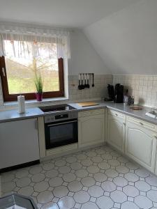 eine Küche mit weißen Schränken, einem Herd und einem Fenster in der Unterkunft Hof Beuck in Travenhorst