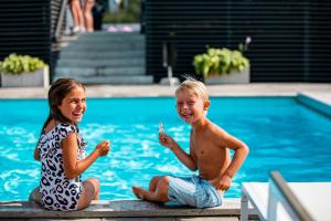a boy and a girl sitting next to a swimming pool at First Hotel Kokoloko in Visby
