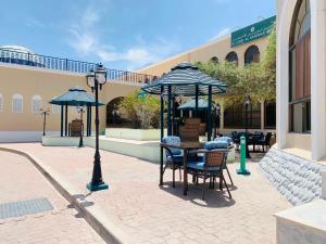 un patio con mesa, sillas y sombrillas en Jabal Akhdhar Hotel en Al ‘Aqar