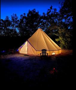 Tienda blanca con silla en un campo en Camping Arbre de Vie en Montagnac