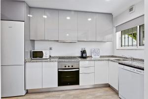 een witte keuken met witte kasten en een magnetron bij Vale San Antonio Apartments in Almancil +1 foto
