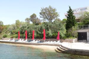 - un groupe de parasols et de chaises rouges sur une plage dans l'établissement Vila Stosic, à Ražanac